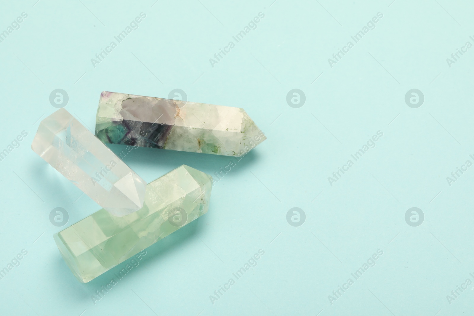 Photo of Beautiful natural gemstones on light blue background, above view. Space for text