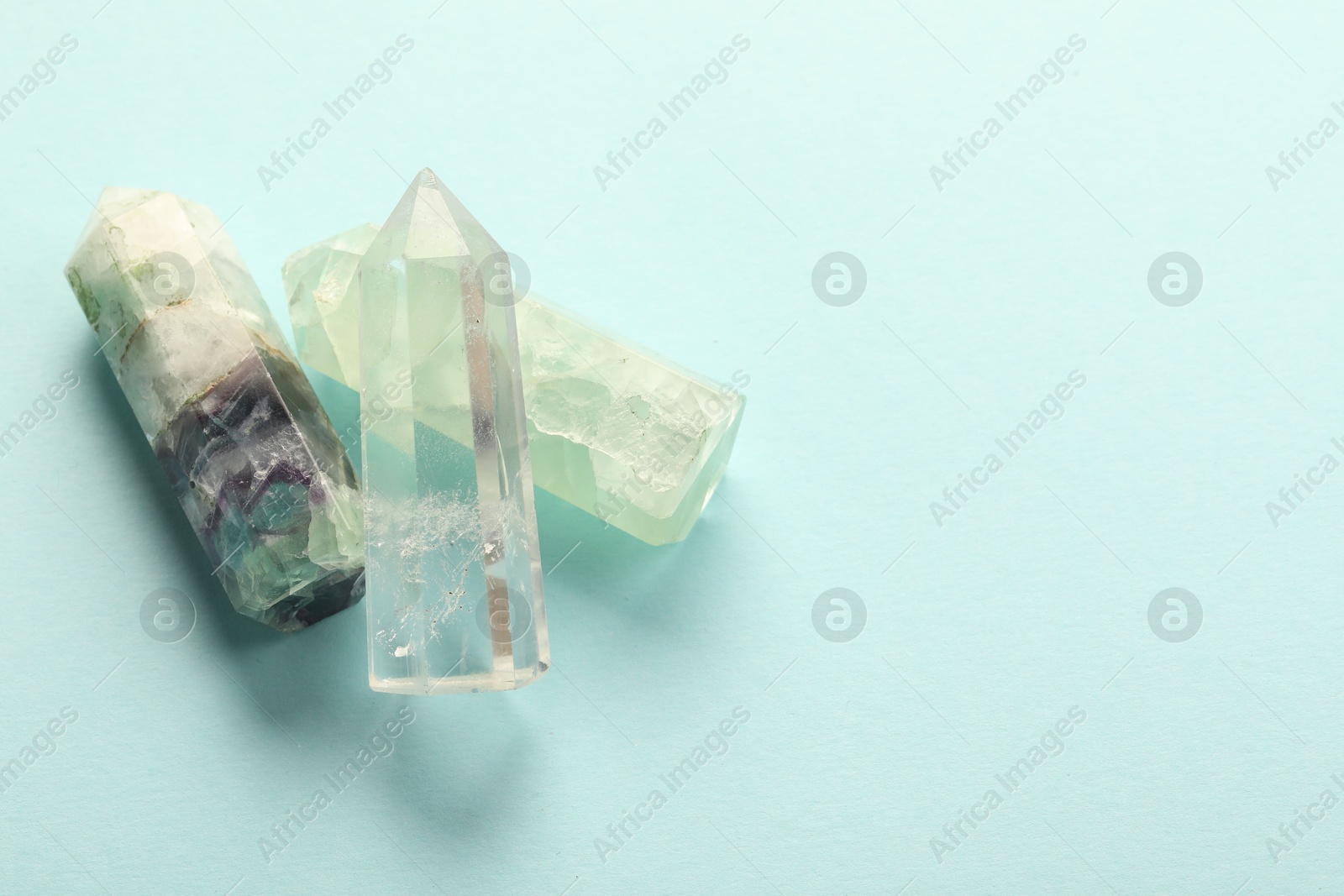 Photo of Beautiful natural gemstones on light blue background, top view. Space for text