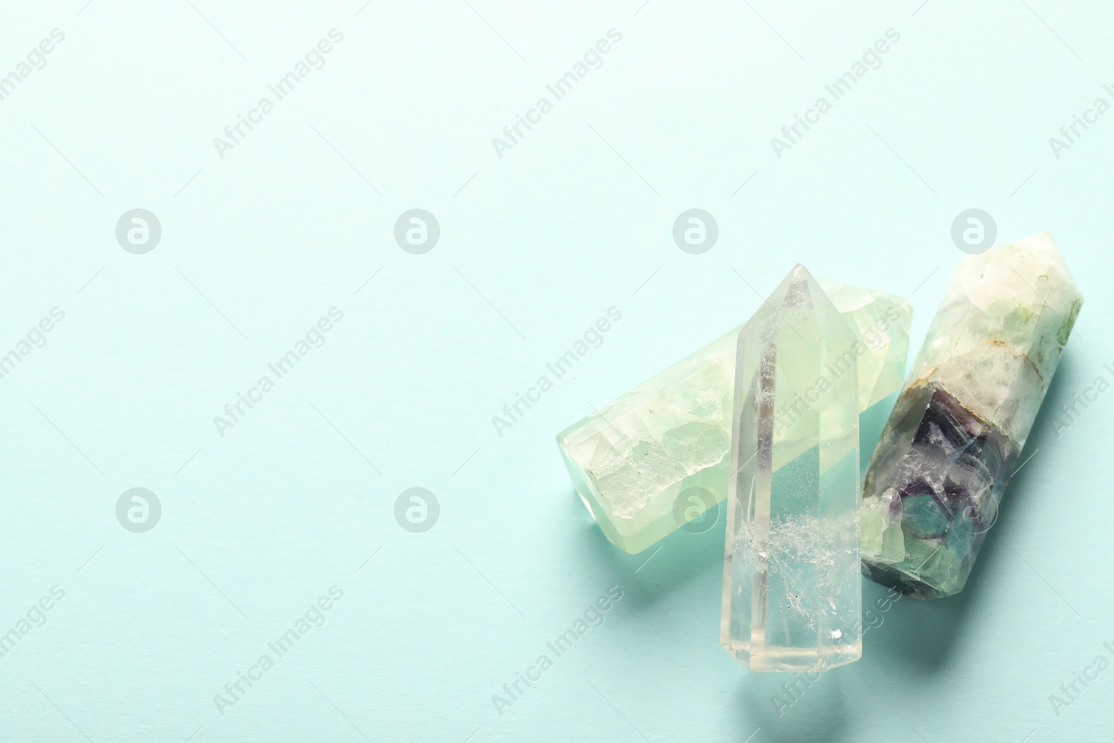 Photo of Beautiful natural gemstones on light blue background, top view. Space for text