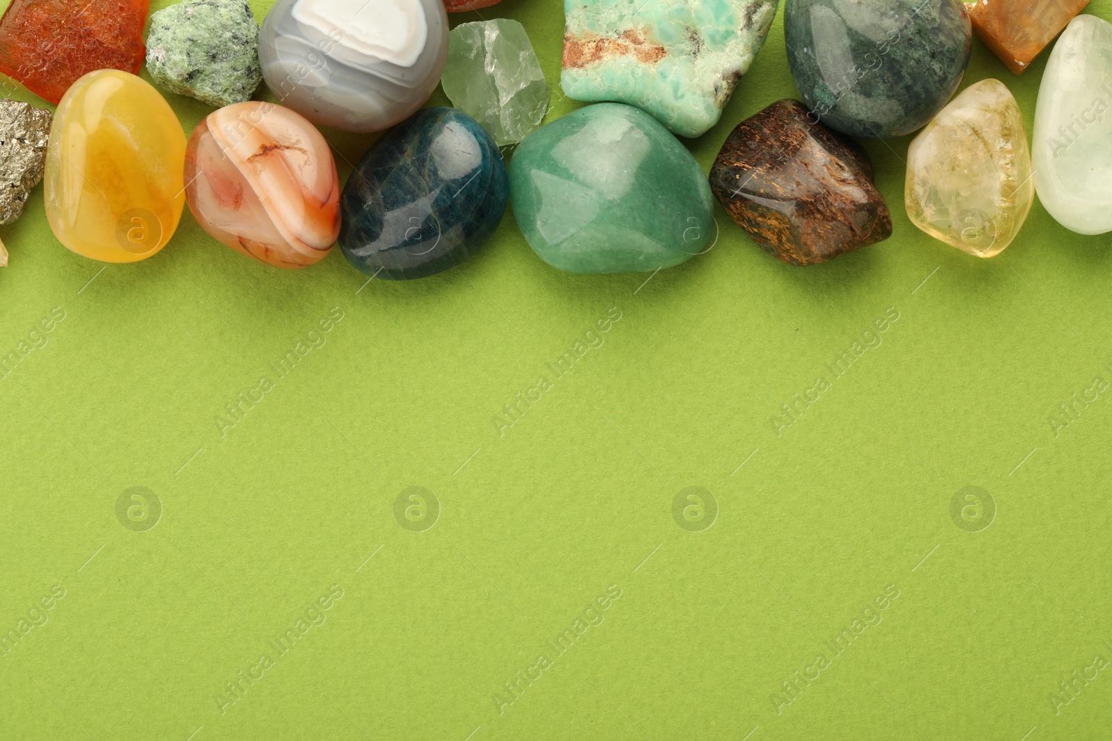 Photo of Beautiful natural gemstones on green background, flat lay. Space for text