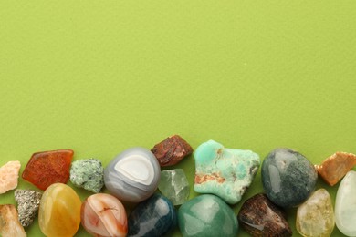 Photo of Beautiful natural gemstones on green background, flat lay. Space for text