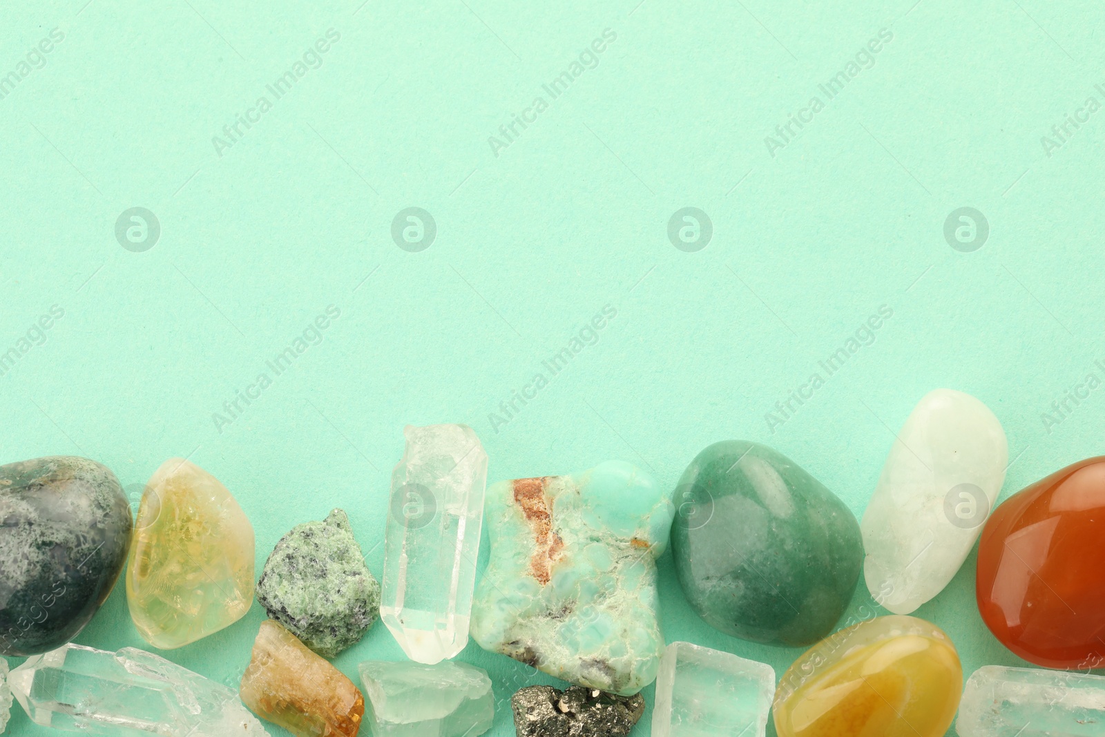 Photo of Beautiful natural gemstones on turquoise background, flat lay. Space for text