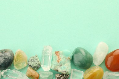 Photo of Beautiful natural gemstones on turquoise background, flat lay. Space for text