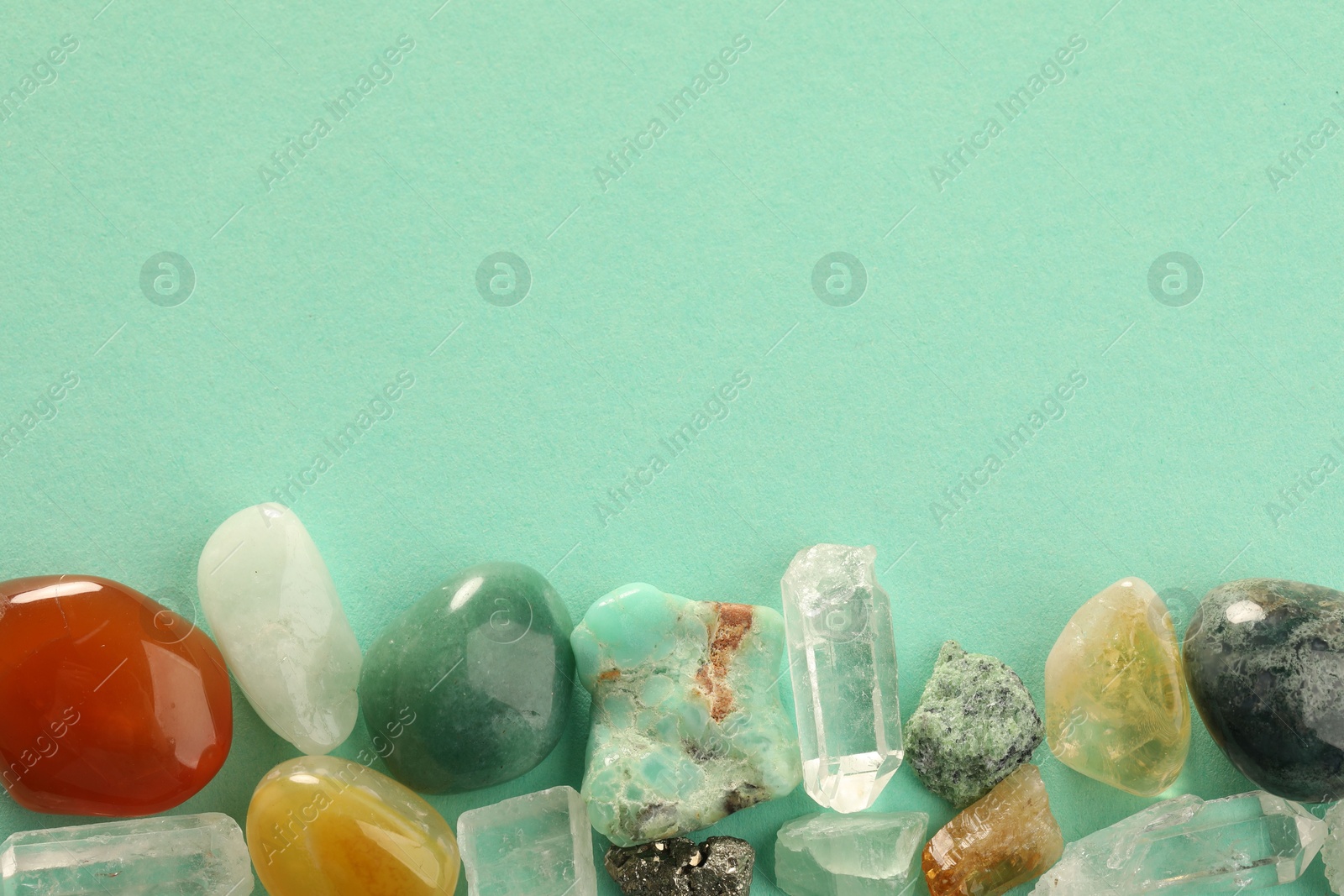 Photo of Beautiful natural gemstones on turquoise background, flat lay. Space for text