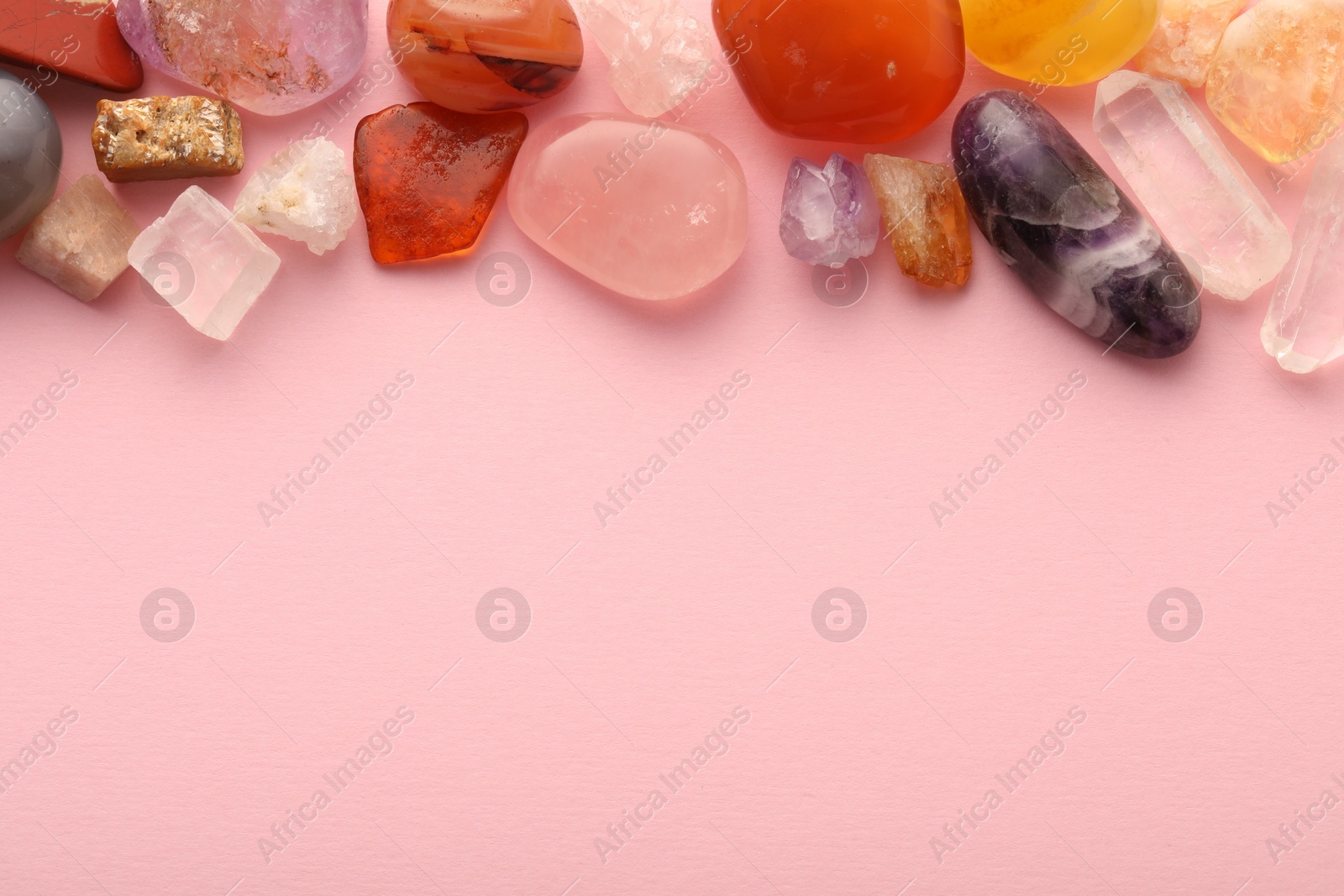 Photo of Beautiful natural gemstones on light pink background, flat lay. Space for text