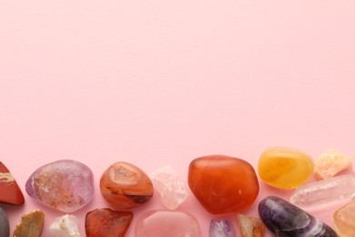 Photo of Beautiful natural gemstones on light pink background, flat lay. Space for text