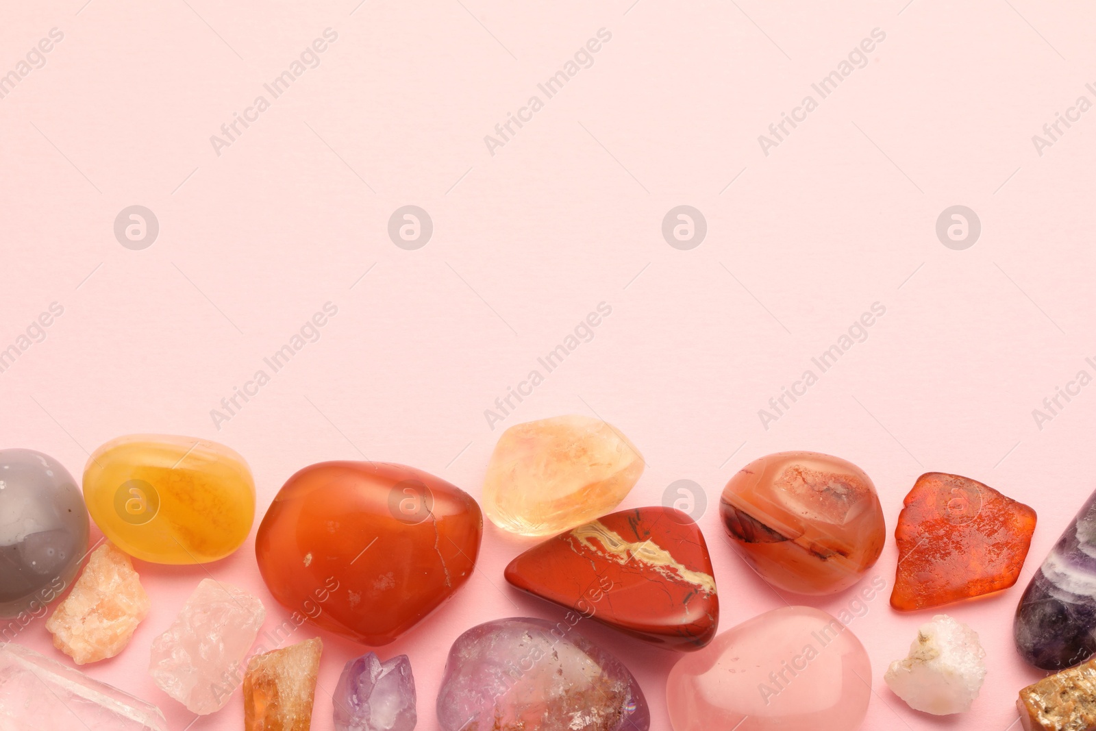 Photo of Beautiful natural gemstones on light pink background, flat lay. Space for text