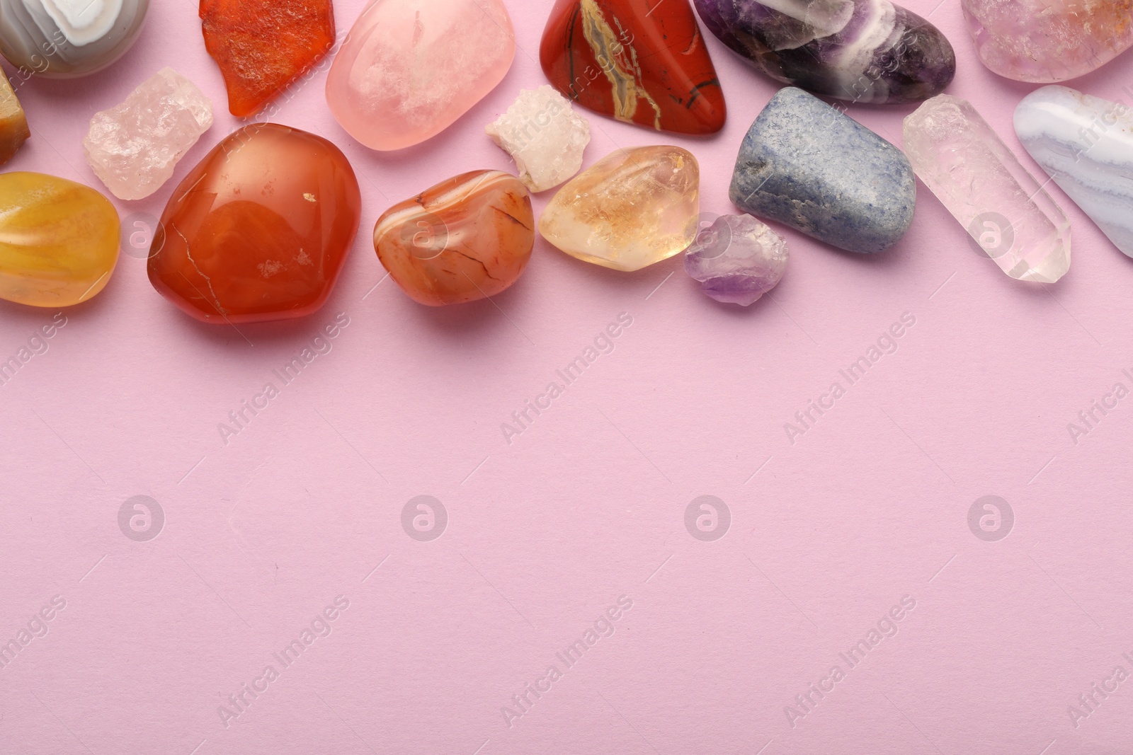 Photo of Beautiful natural gemstones on light pink background, flat lay. Space for text