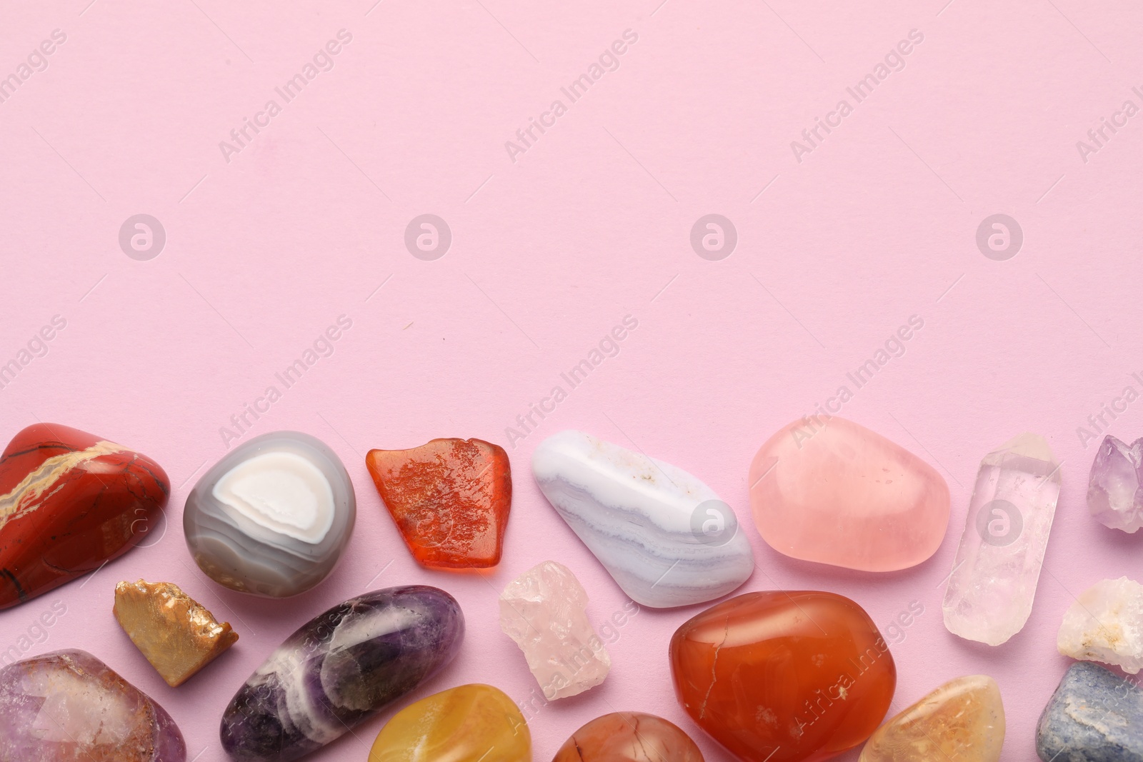 Photo of Beautiful natural gemstones on light pink background, flat lay. Space for text