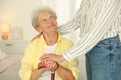 Photo of Senior woman with walking cane and her granddaughter at home