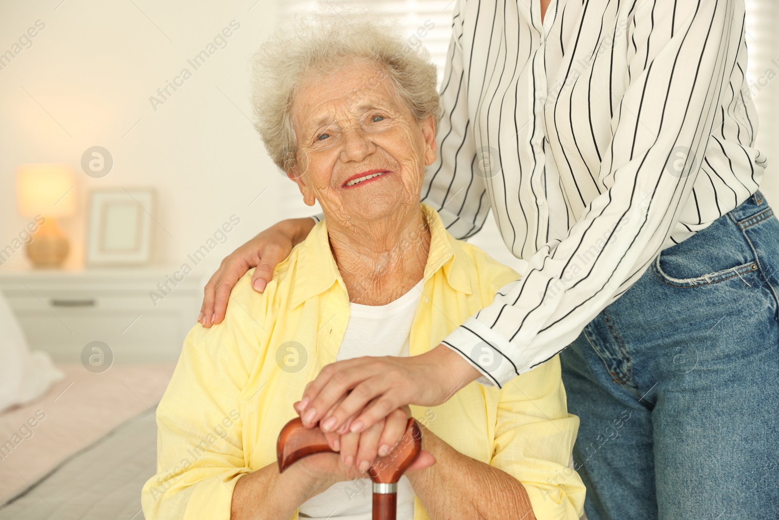 Photo of Senior woman with walking cane and her granddaughter at home