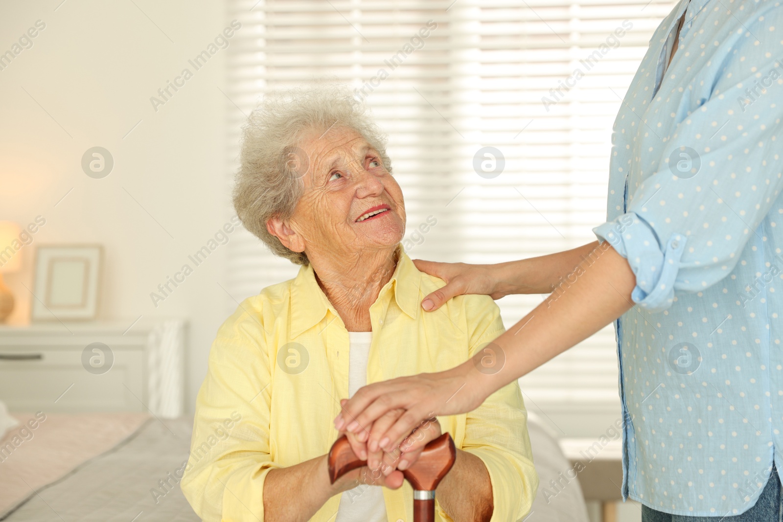 Photo of Senior woman with walking cane and her granddaughter at home