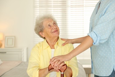 Photo of Senior woman with walking cane and her granddaughter at home