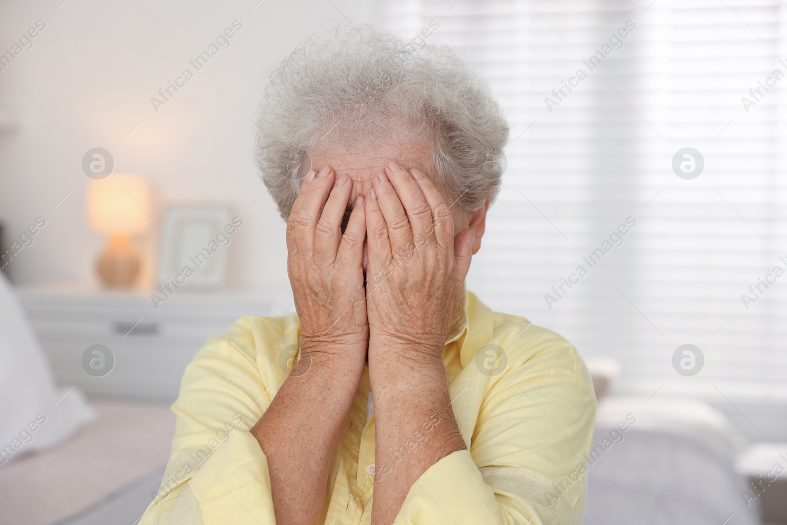 Photo of Senior woman closing her eyes with hands indoors