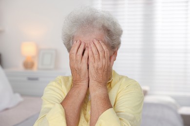 Photo of Senior woman closing her eyes with hands indoors