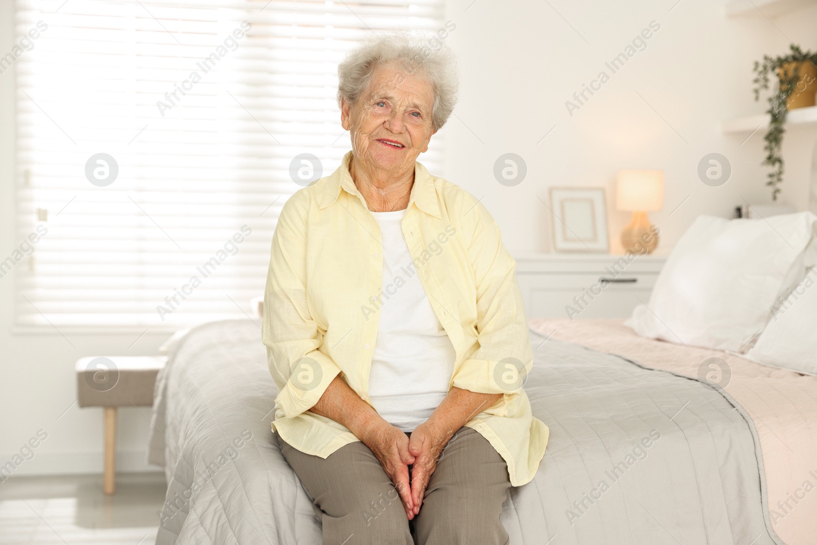 Photo of Beautiful senior woman sitting on bed at home