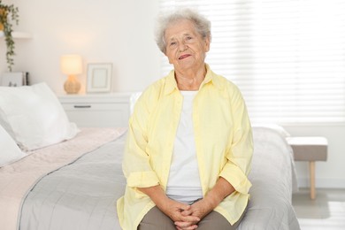 Photo of Beautiful senior woman sitting on bed at home