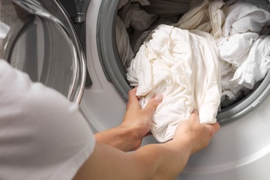 Photo of Woman taking clean clothes out of washing machine, closeup