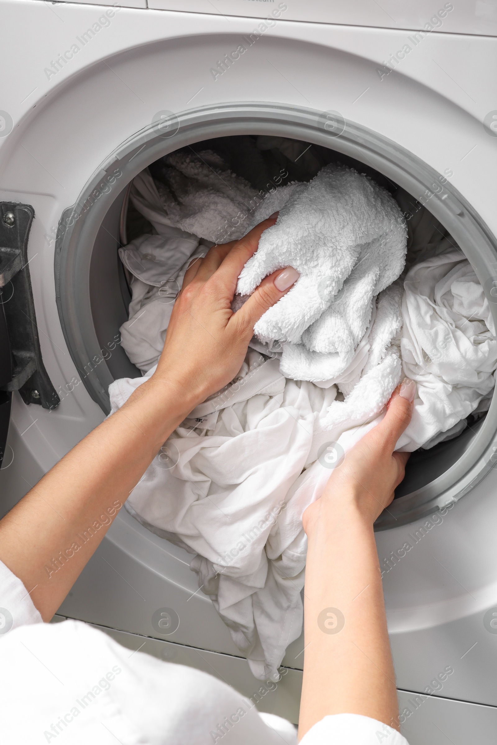 Photo of Woman taking clean clothes out of washing machine, closeup