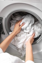 Photo of Woman taking clean clothes out of washing machine, closeup