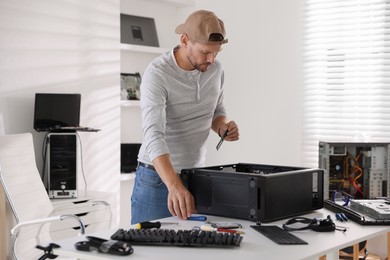 Photo of Man assembling new computer at white table