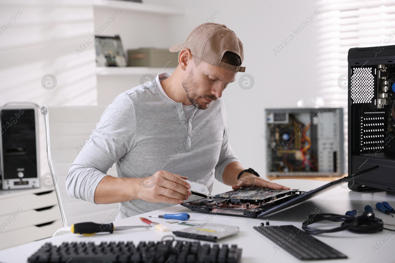 Photo of Man fixing old laptop at white table