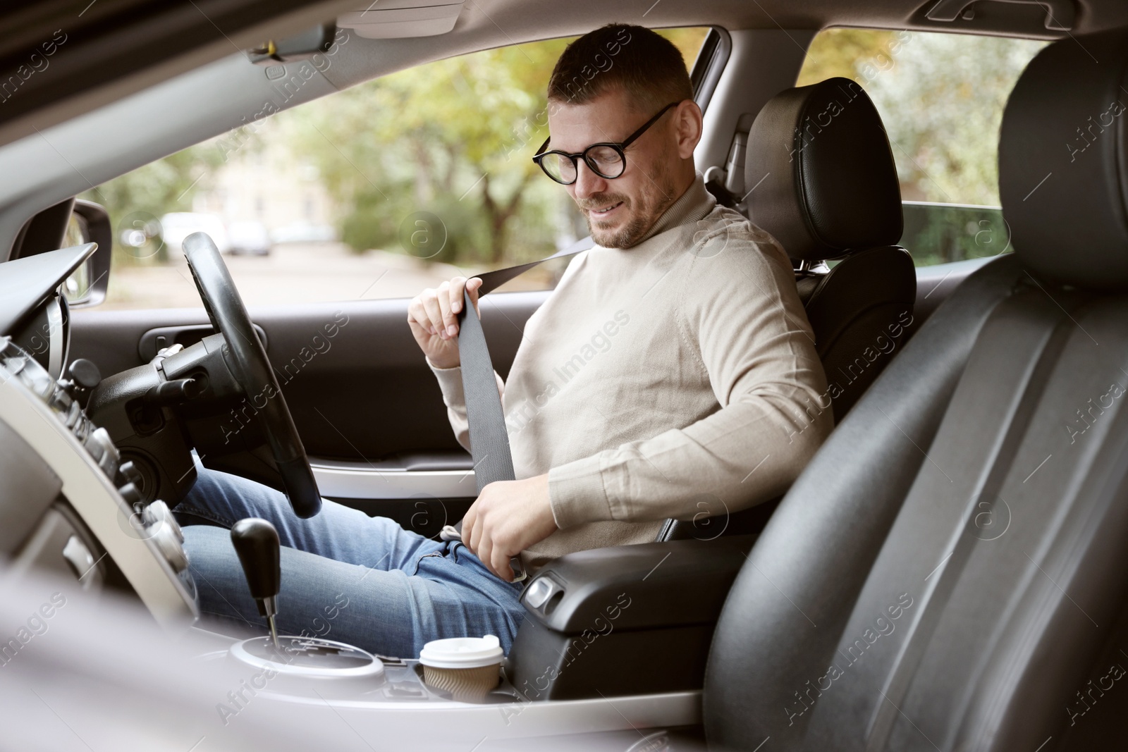 Photo of Man fastening seat belt in modern car