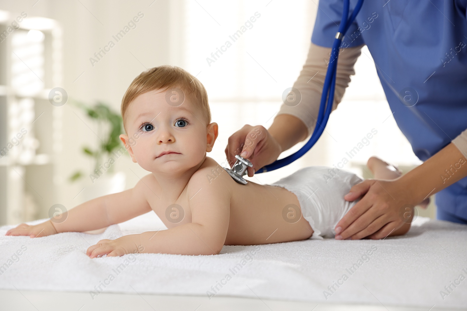 Photo of Pediatrician examining little child with stethoscope in clinic, closeup. Checking baby's health