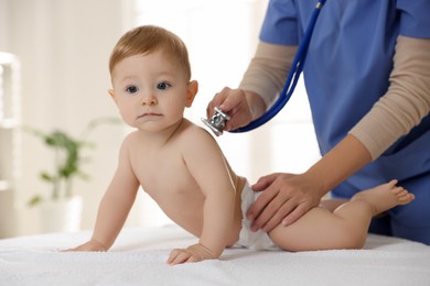 Photo of Pediatrician examining little child with stethoscope in clinic, closeup. Checking baby's health