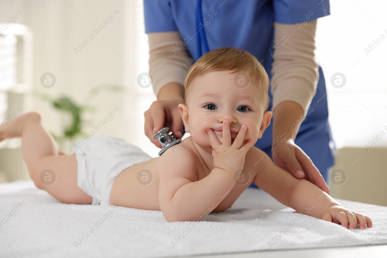 Photo of Pediatrician examining little child with stethoscope in clinic, closeup. Checking baby's health