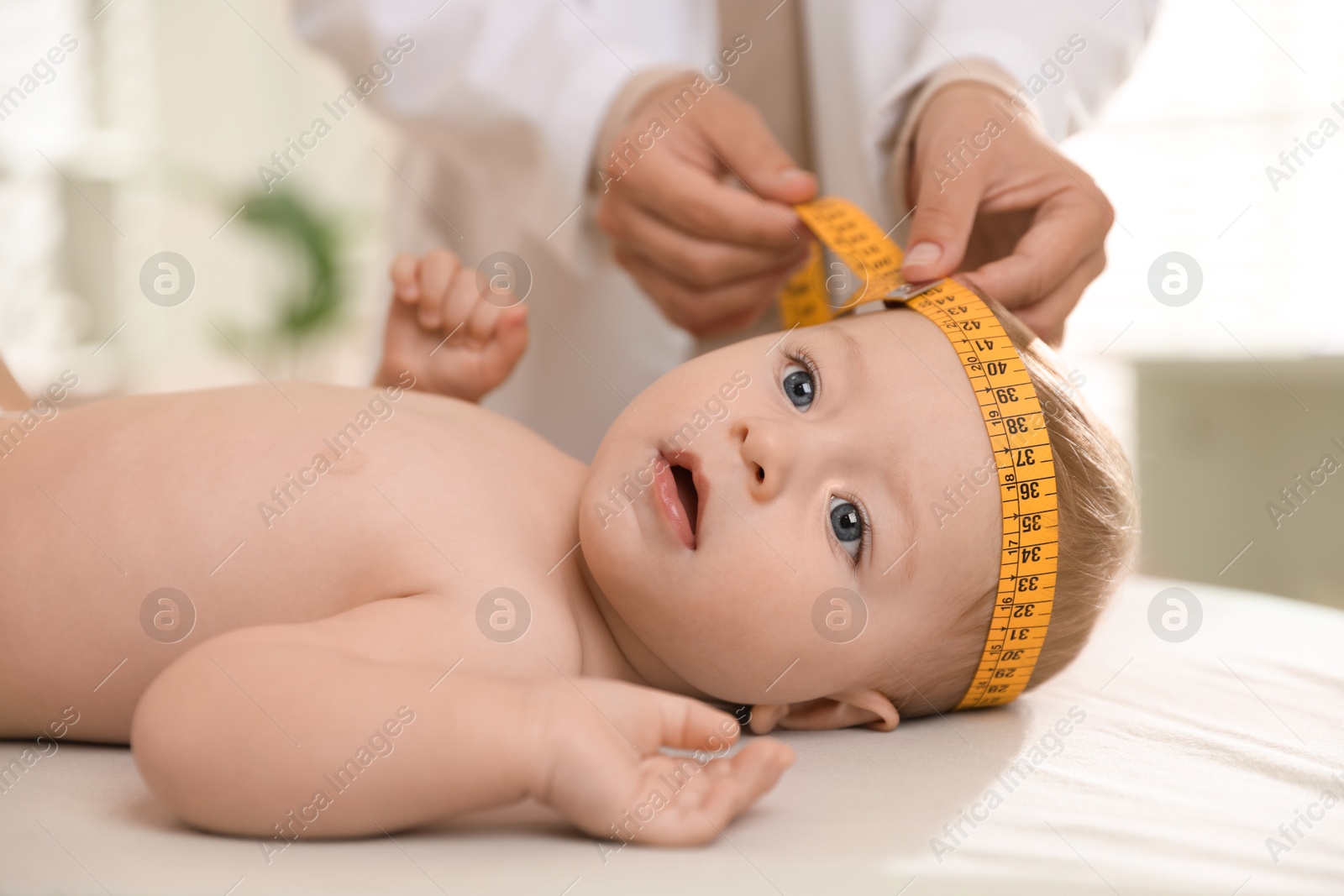 Photo of Pediatrician measuring little baby's head in clinic, closeup