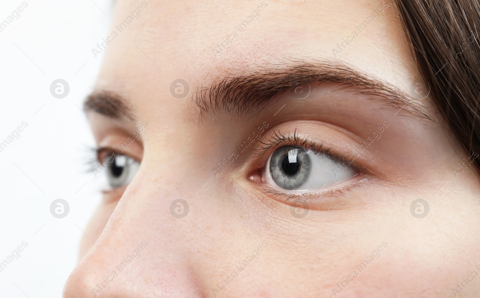 Photo of Closeup view of young woman with beautiful blue eyes on white background