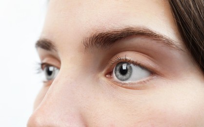 Photo of Closeup view of young woman with beautiful blue eyes on white background