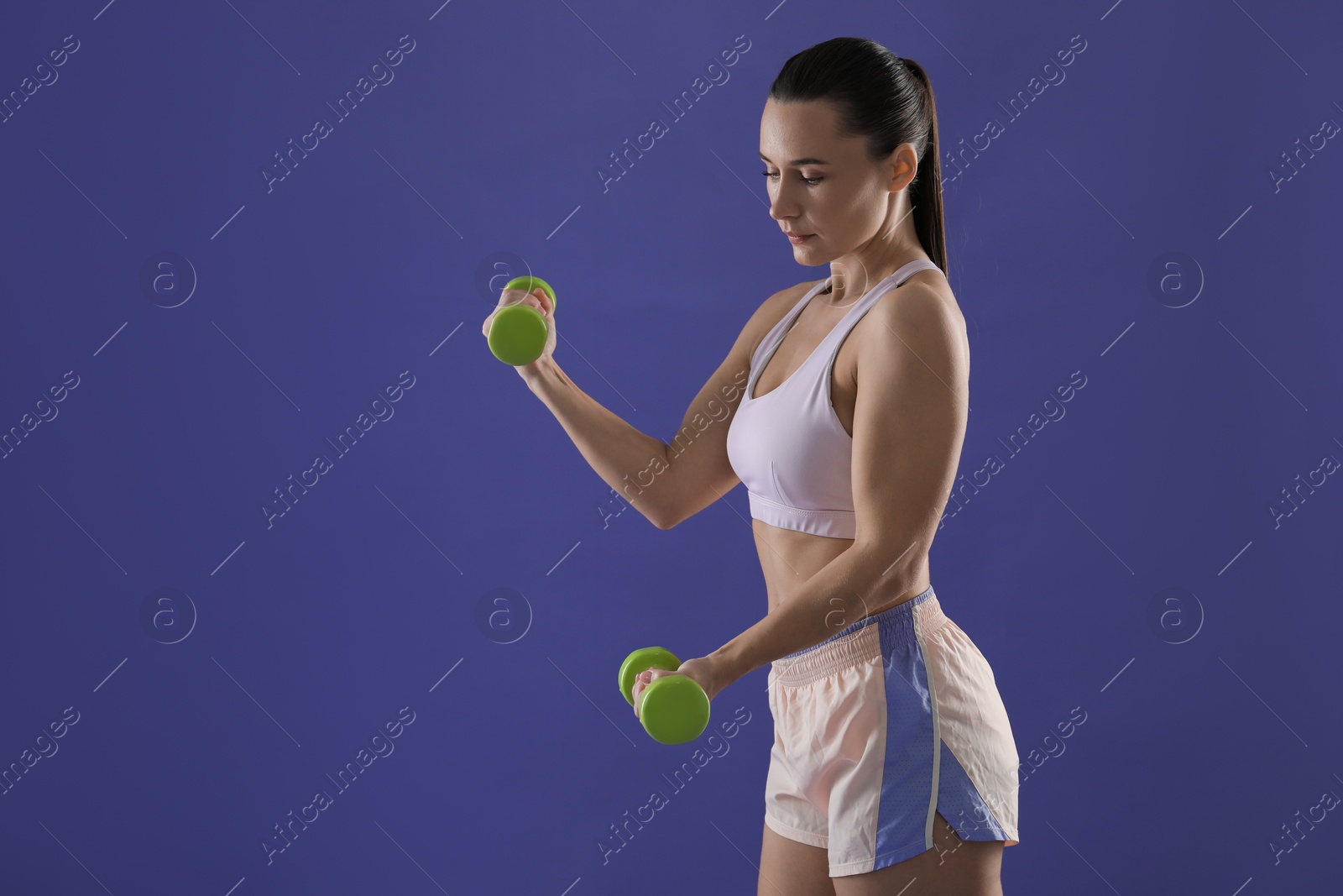 Photo of Woman exercising with dumbbells on purple background, space for text