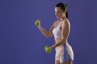 Photo of Woman exercising with dumbbells on purple background, space for text