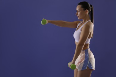 Photo of Woman exercising with dumbbells on purple background, space for text