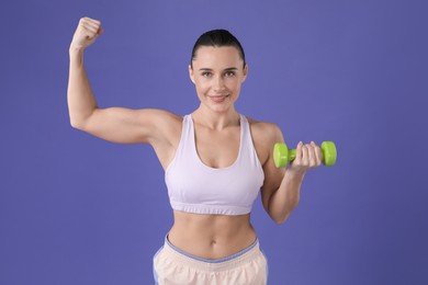 Photo of Woman exercising with dumbbell on purple background