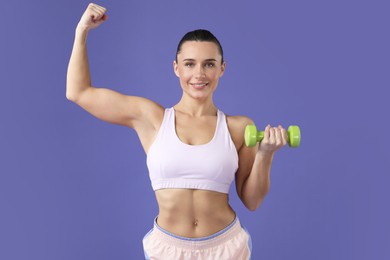 Photo of Woman exercising with dumbbell on purple background