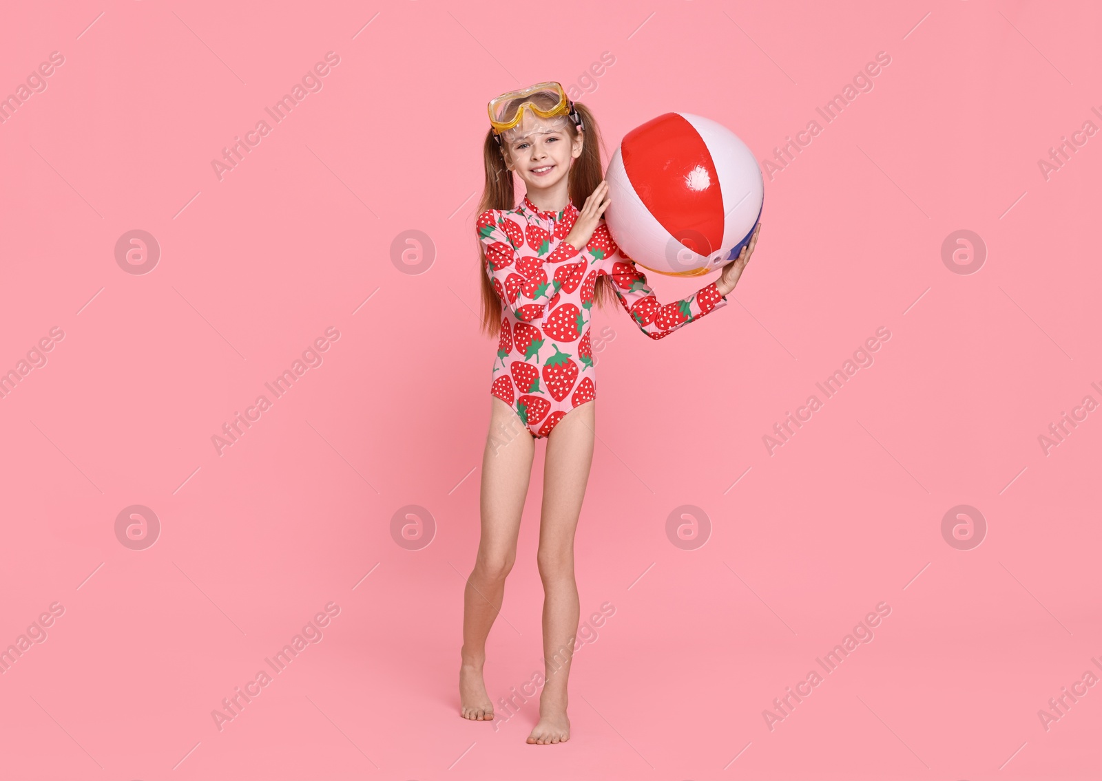 Photo of Happy girl in beachwear with diving mask and inflatable ball on pink background