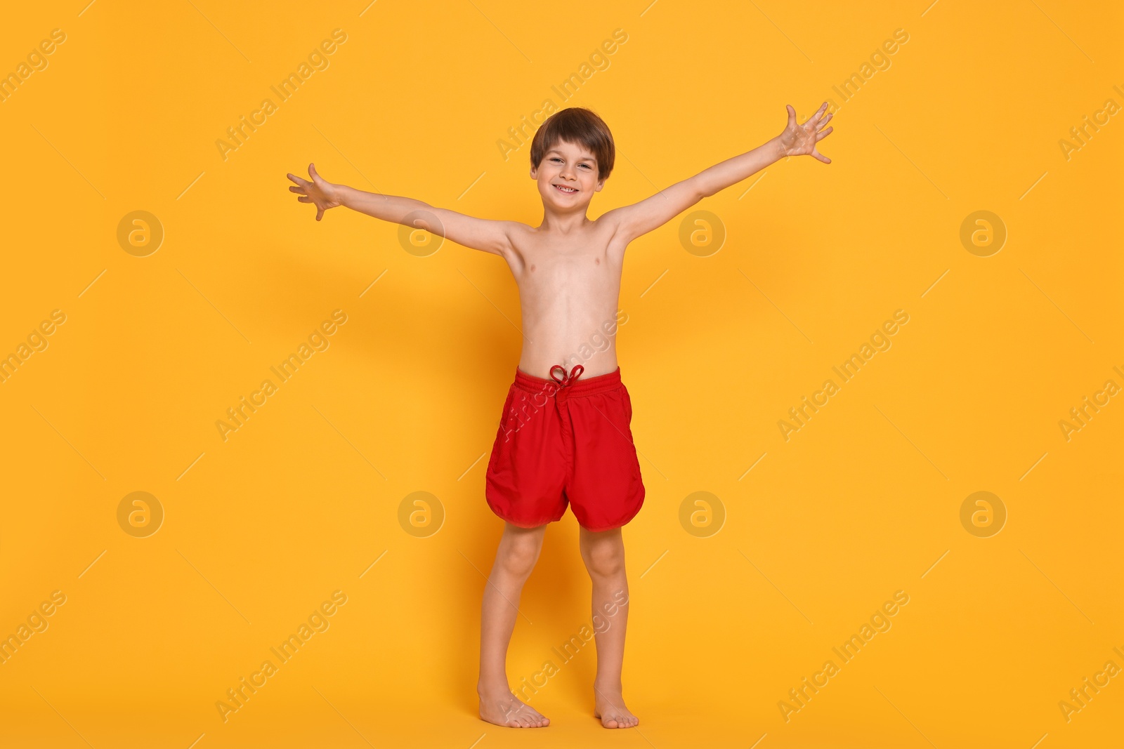 Photo of Happy little boy in beachwear on orange background