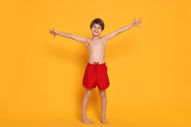 Photo of Happy little boy in beachwear on orange background