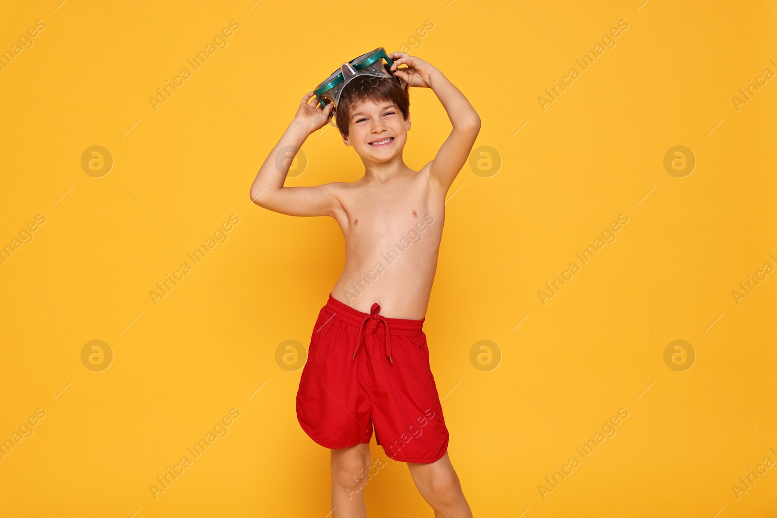 Photo of Little boy in beachwear with diving mask on orange background