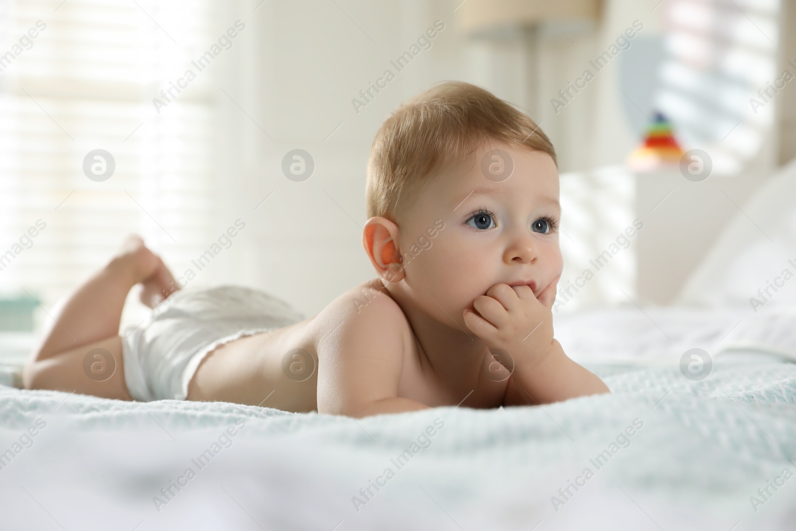 Photo of Cute little baby in diaper on bed at home