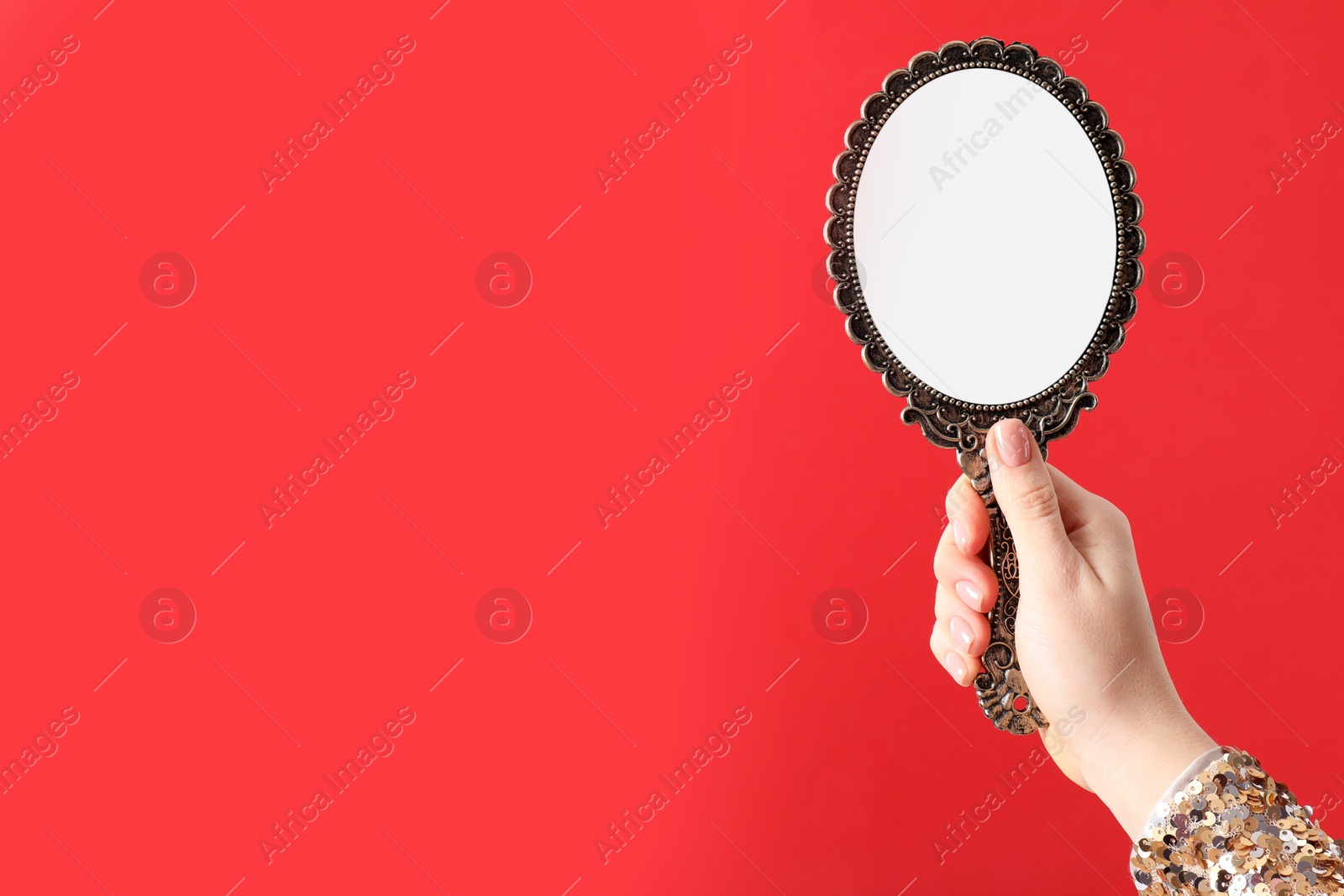 Photo of Woman holding vintage mirror on red background, closeup. Space for text