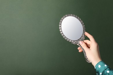 Woman holding vintage mirror on green background, closeup. Space for text