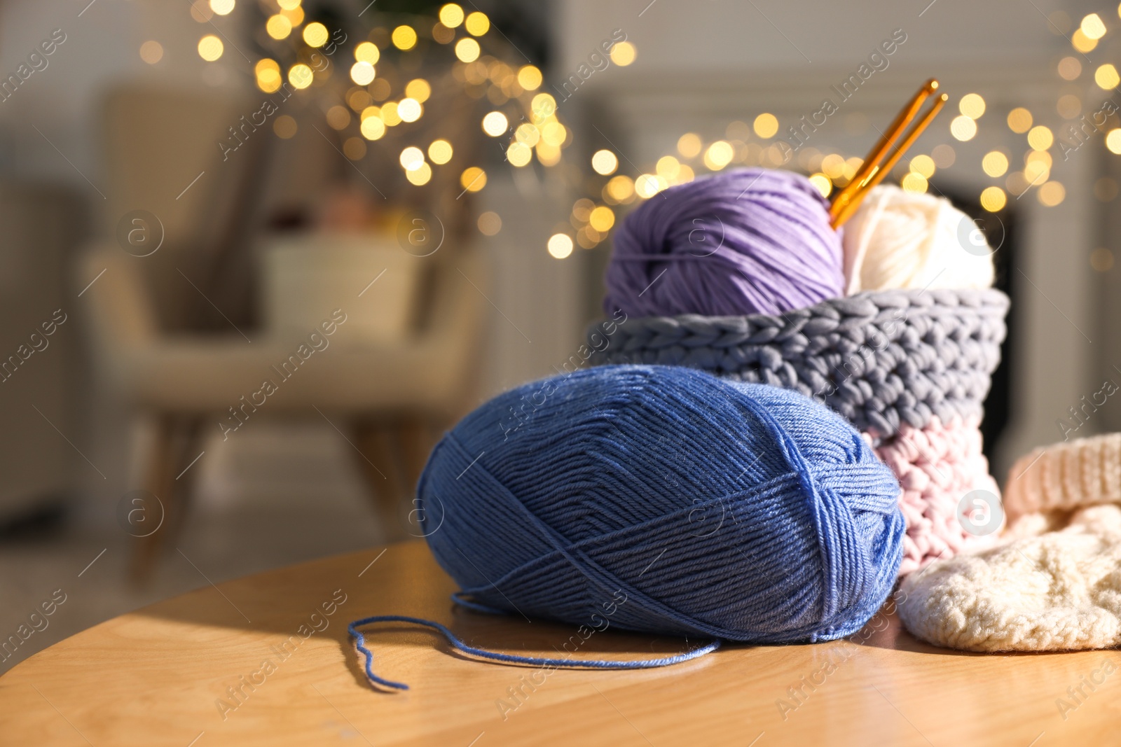 Photo of Colorful yarns, knitted mittens and crochet hooks on wooden table indoors, closeup. Space for text