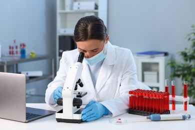 Photo of Laboratory testing. Doctor working with microscope at table indoors