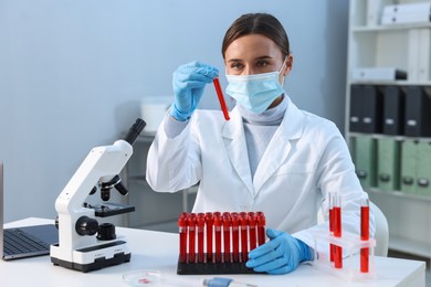 Photo of Laboratory testing. Doctor holding test tube with blood sample at table indoors