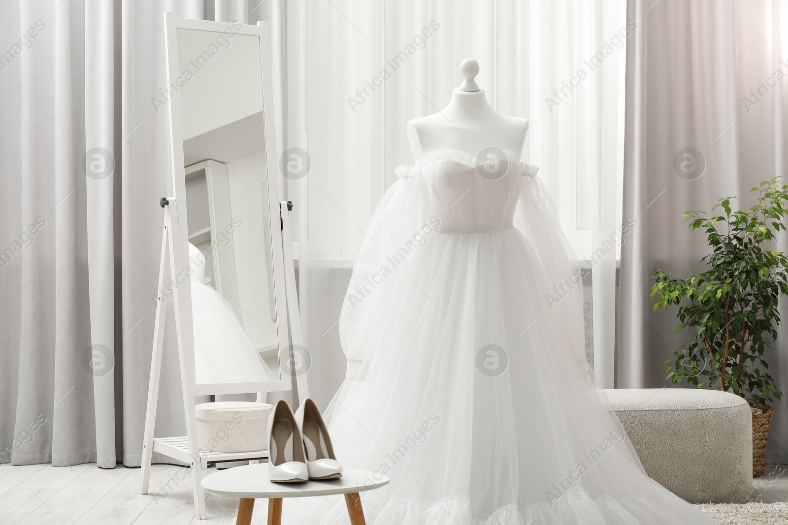 Photo of Beautiful wedding dress on mannequin and shoes in boutique