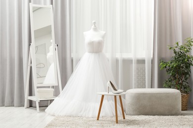 Photo of Beautiful wedding dress on mannequin and shoes in boutique